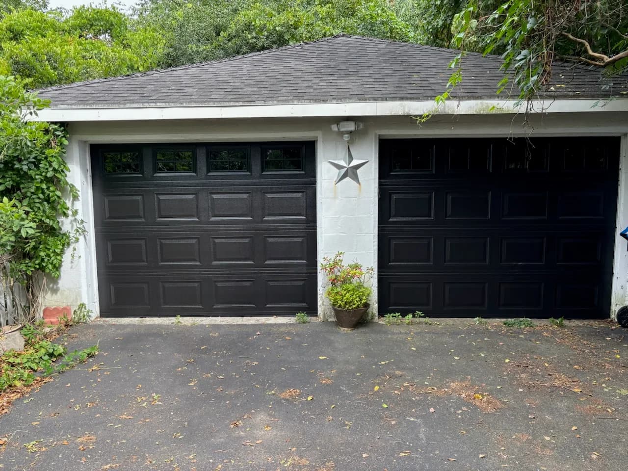 Same garage with two new black raised-panel garage doors installed by Monroe Overhead Door