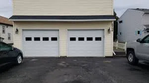 Two single-car garage doors with windows on a cream-sided two-story home