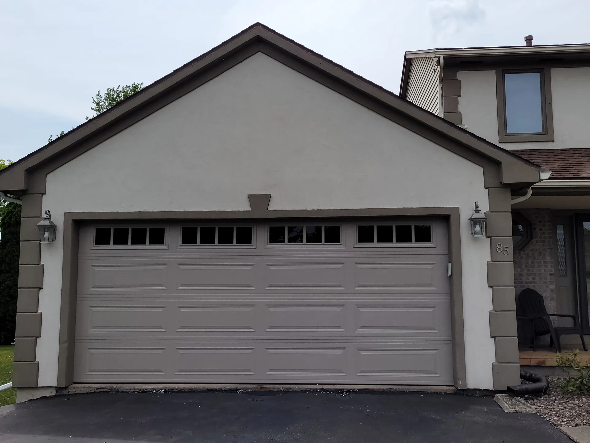 Sandstone raised-panel garage door with prairie-style windows on a stucco home